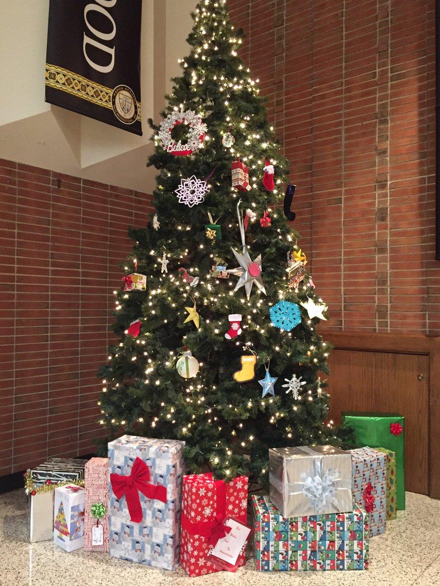 A picture of the beautiful finished Christmas tree. It contains many unique ornaments created by homeroom representatives. There are also a variety of different presents under the tree.