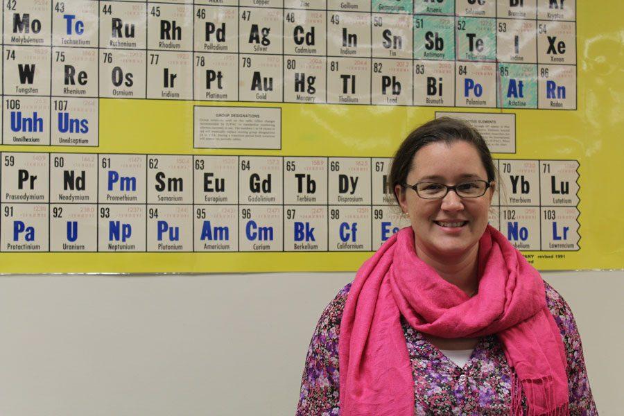 Mrs.+Alinda+poses+in+front+of+the+periodic+table