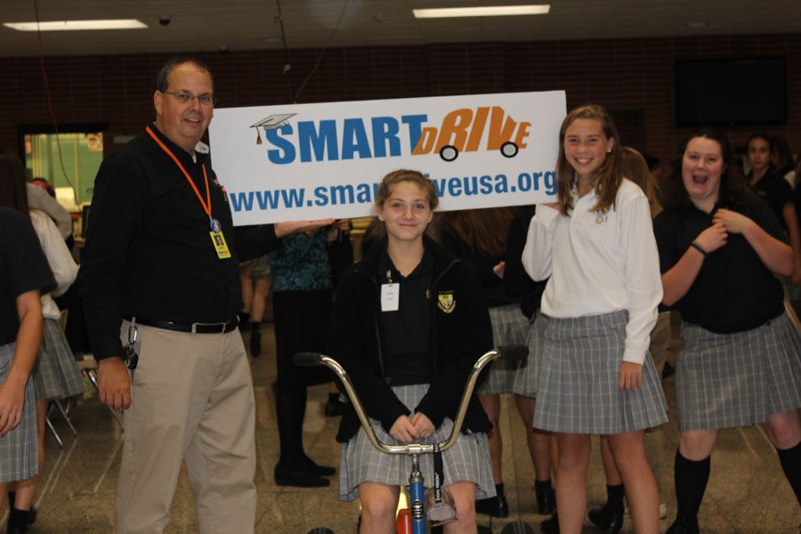 Program coordinator of SmartDrive, Guy VanderLek, smiles with two Padua freshmen, showing off the SmartDrive sign.