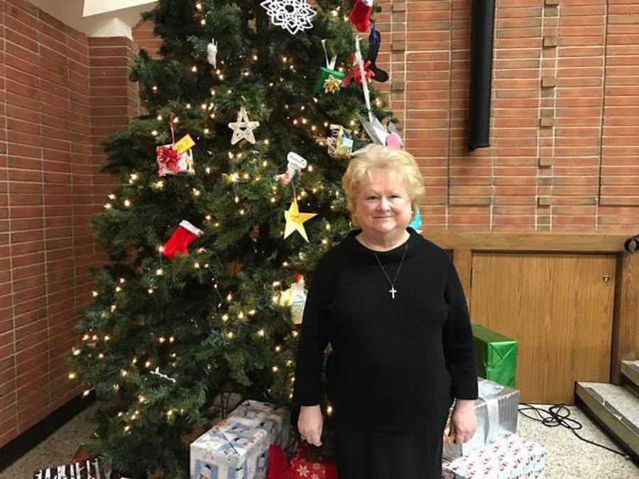 Mrs. Mann gets into the holiday spirit by standing with the Padua Christmas tree