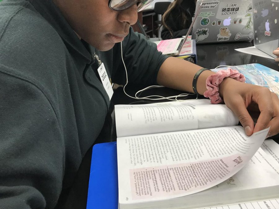 Freshmen looking over her Sacred Scripture textbook.