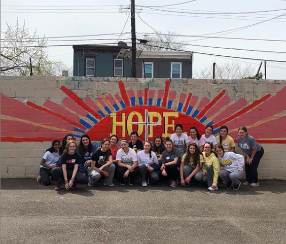 Students pose by a mural on a school playground in Camden. 