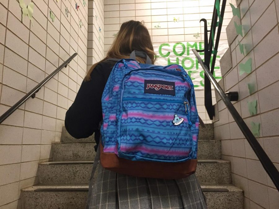 Junior Meghan Freeze walks up the stairs with her backpack. She struggles to walk with a bag that is much heavier than her back can handle.