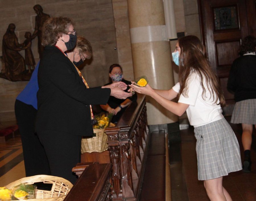 A freshman receives a yellow rose bud from Dr. McClory at Freshman Convocation. Students and families gathered to celebrate the beginning of their high school journey.
