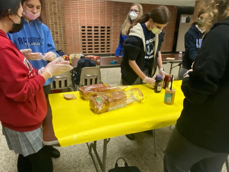 Students put on gloves to prepare to make peanut butter and jelly sandwiches. They also wore a mix of blue and red sweatshirts for Nation day during Spirit Week.