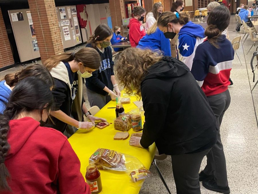 The volunteers spread jelly and peanut butter onto the sandwiches while others packaged them. Many had to roll up the sleeves of their nation themed sweatshirt to be involved.